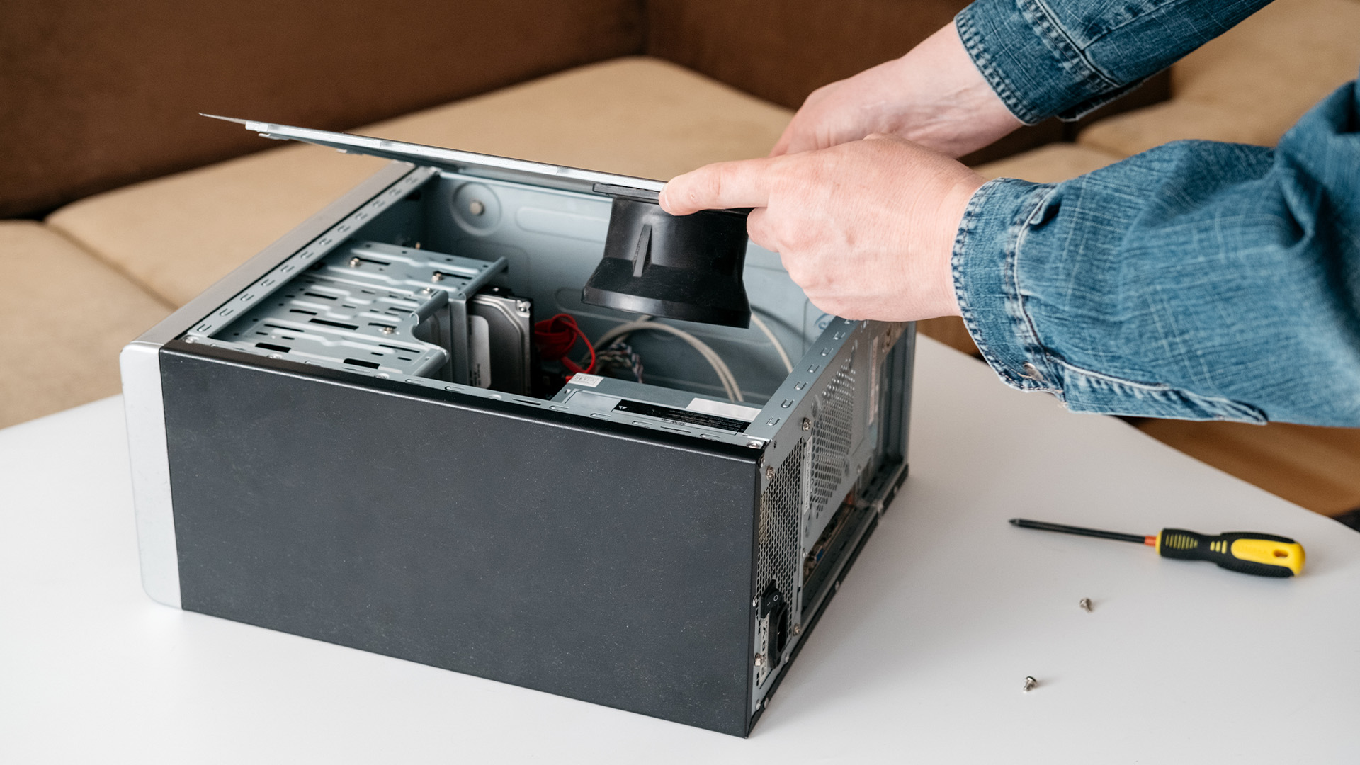 A person removing the side panel of a computer case during hardware maintenance.