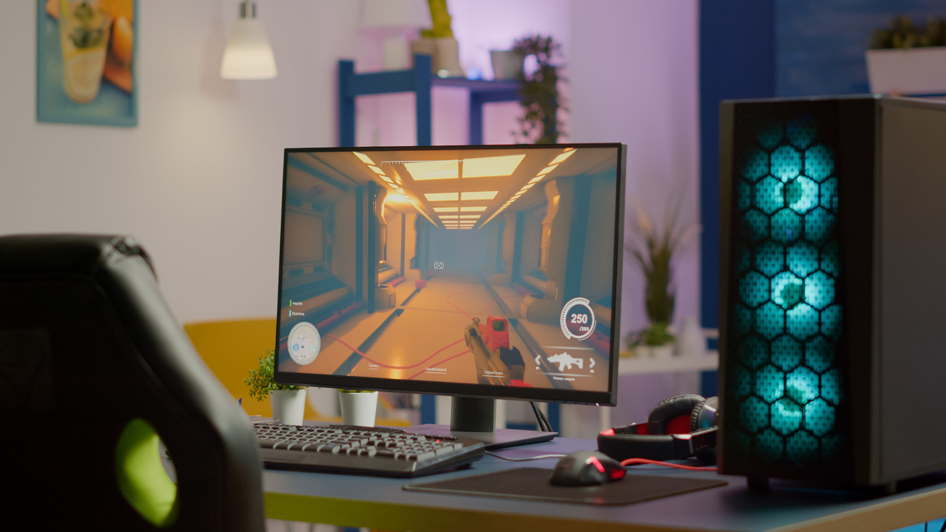 An RGB gaming PC tower and a monitor displaying a first-person video game on a blue desk.