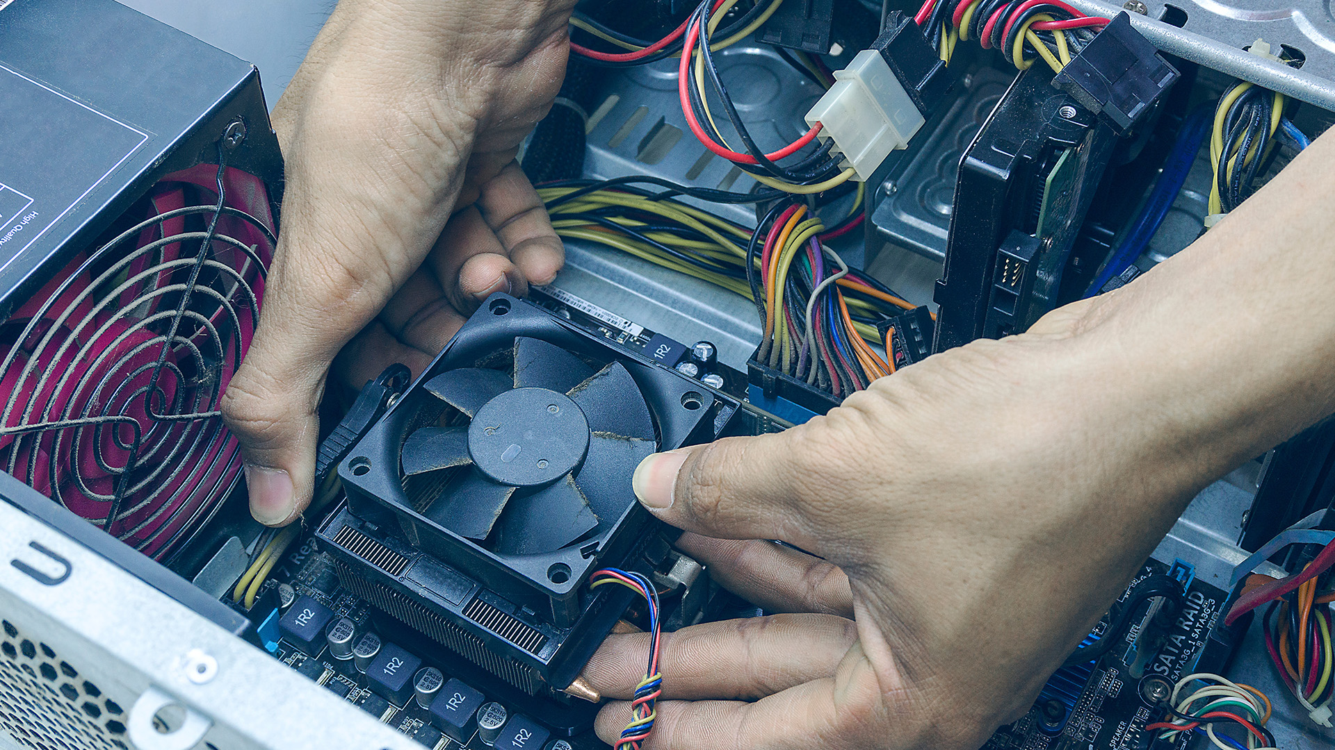 person carefully installing a CPU cooling fan onto a computer motherboard.