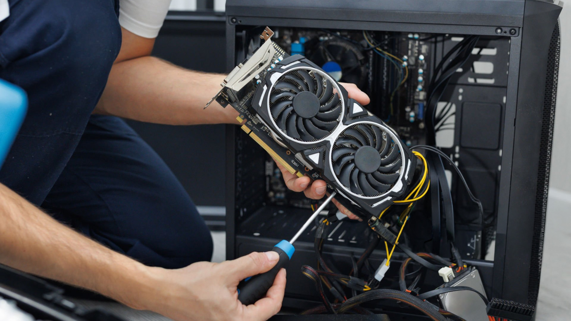 Technician using a screwdriver to repair a PC graphics card.