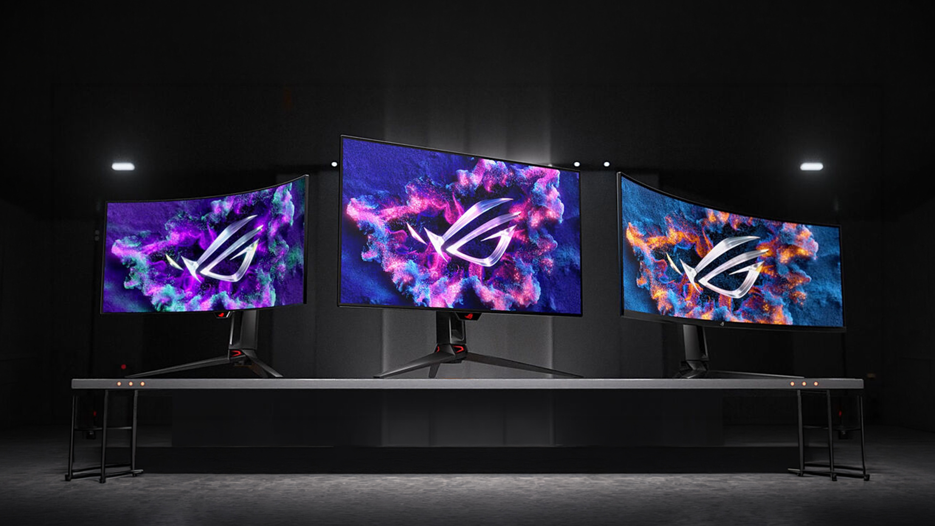 Three ASUS ROG curved gaming monitors arranged on a long desk.
