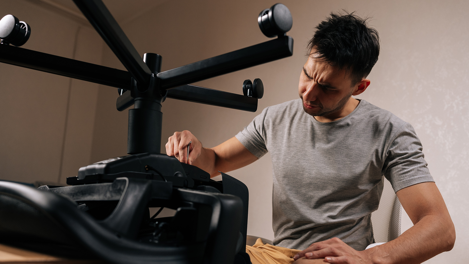 A person inspecting and troubleshooting the base connection of a gaming chair.