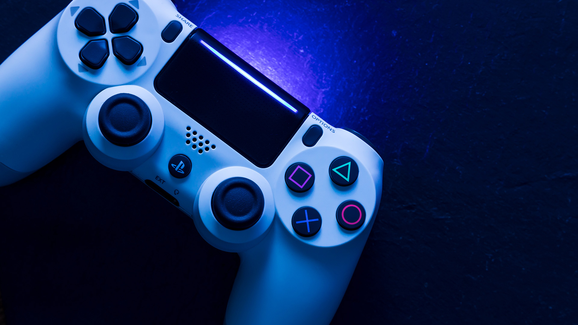 White PlayStation controller illuminated with a blue glow.