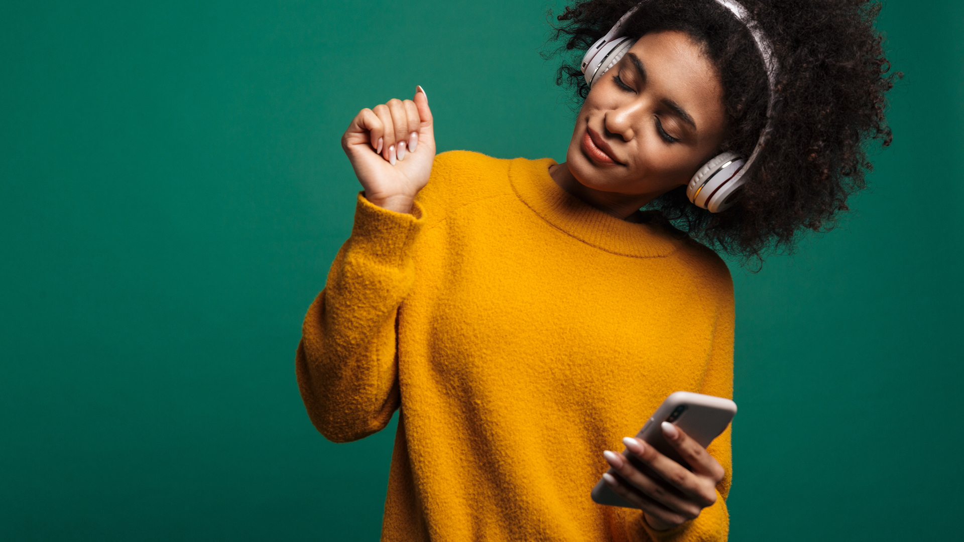 Woman dancing while listening to music with white wireless headphones.