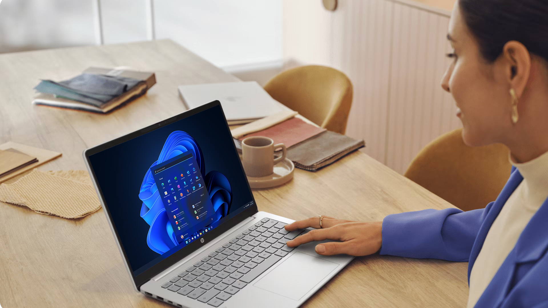 A woman working on a laptop running Windows 11 at a wooden table.