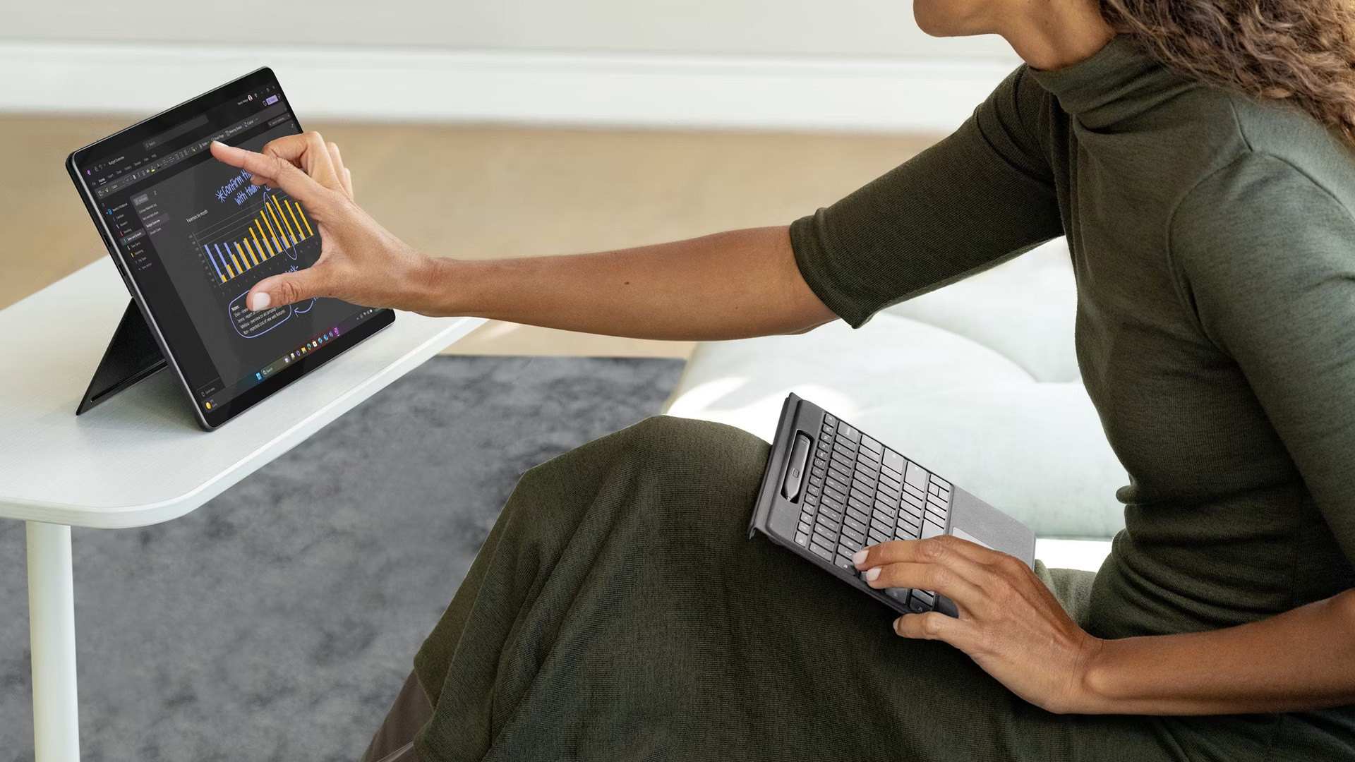 A woman interacting with a Microsoft Surface Pro tablet touchscreen while holding its detachable keyboard.