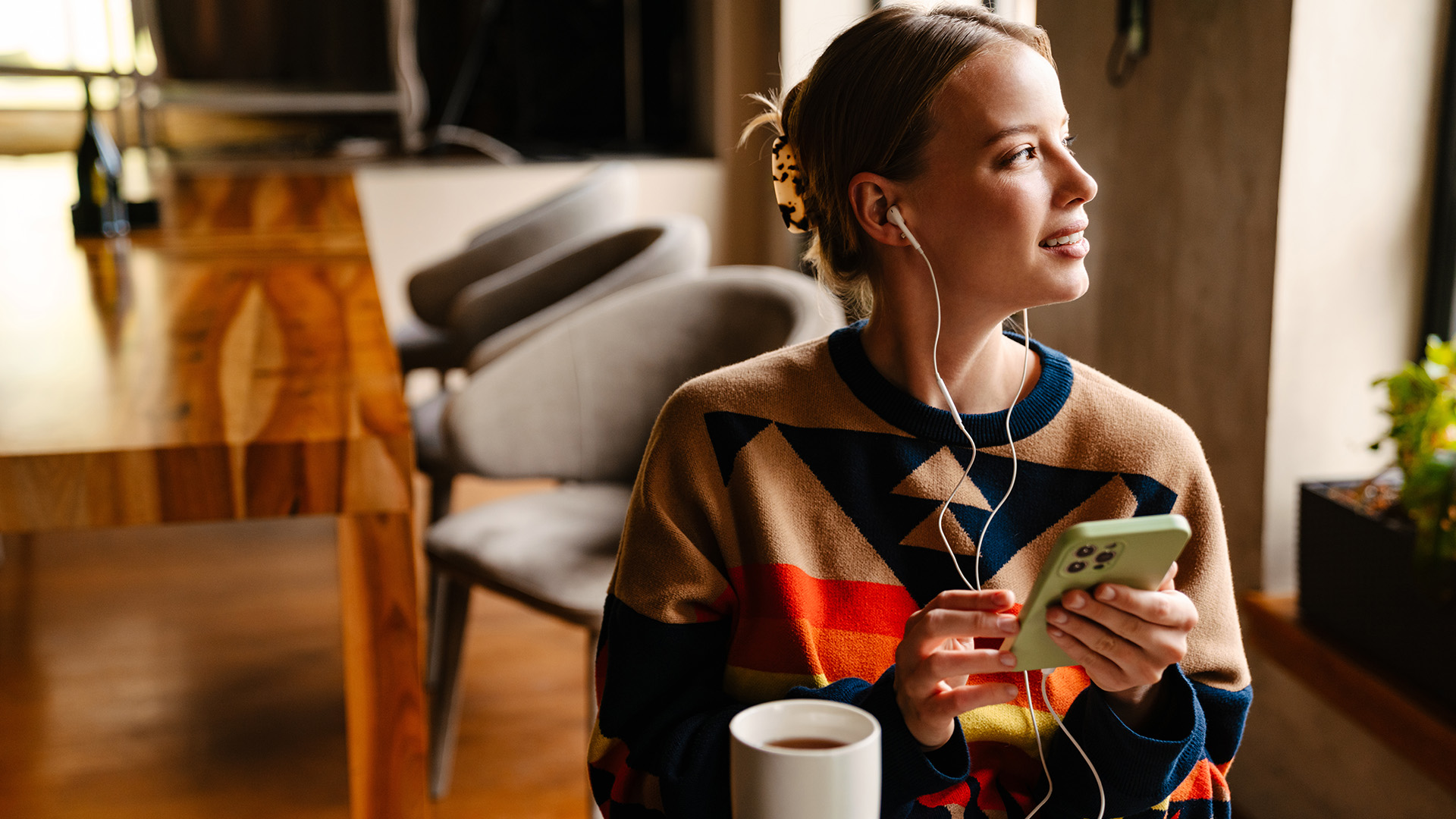 Woman using wired earphones while holding her smartphone.